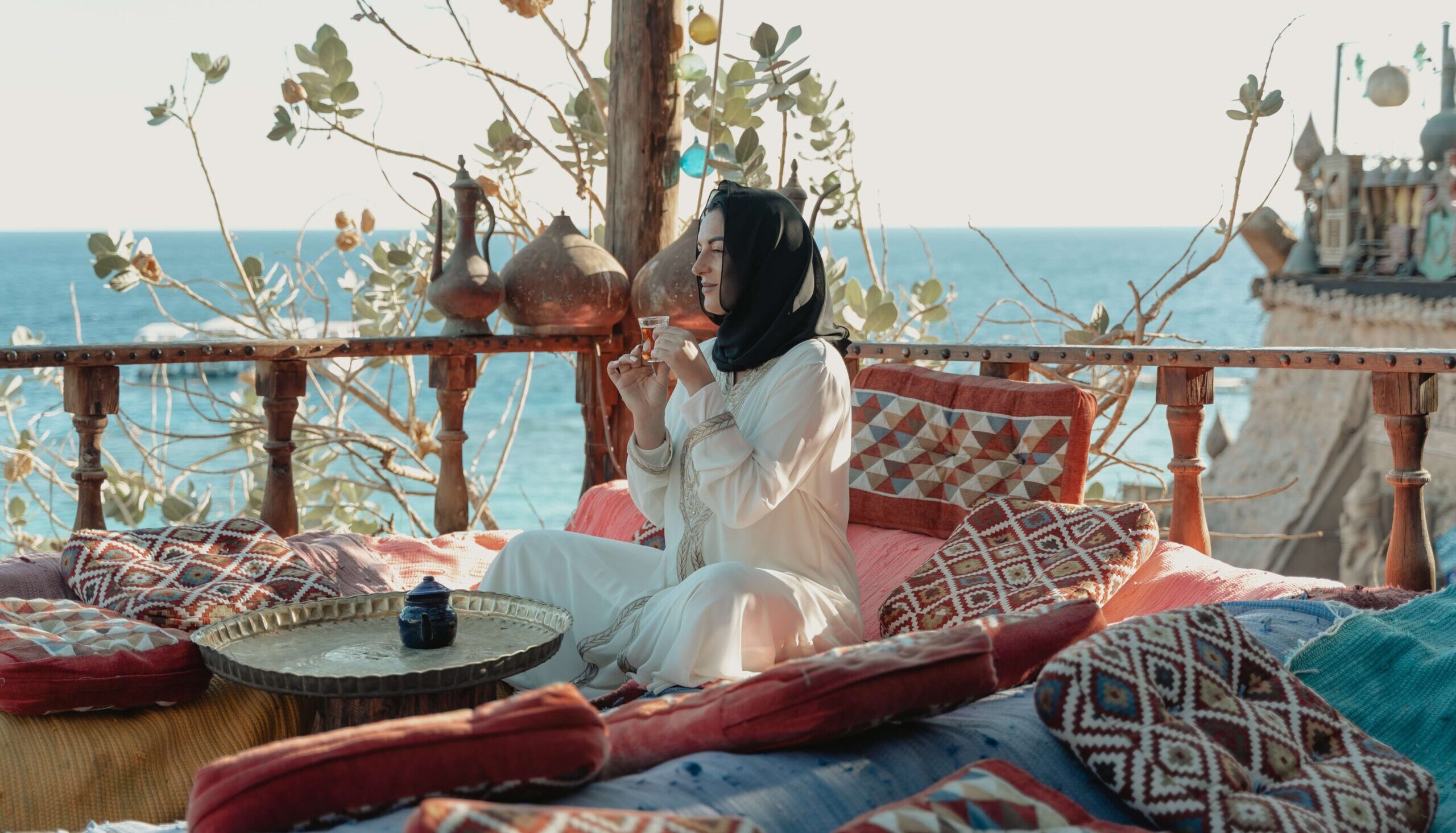 woman sipping tea in lounge overlooking sea