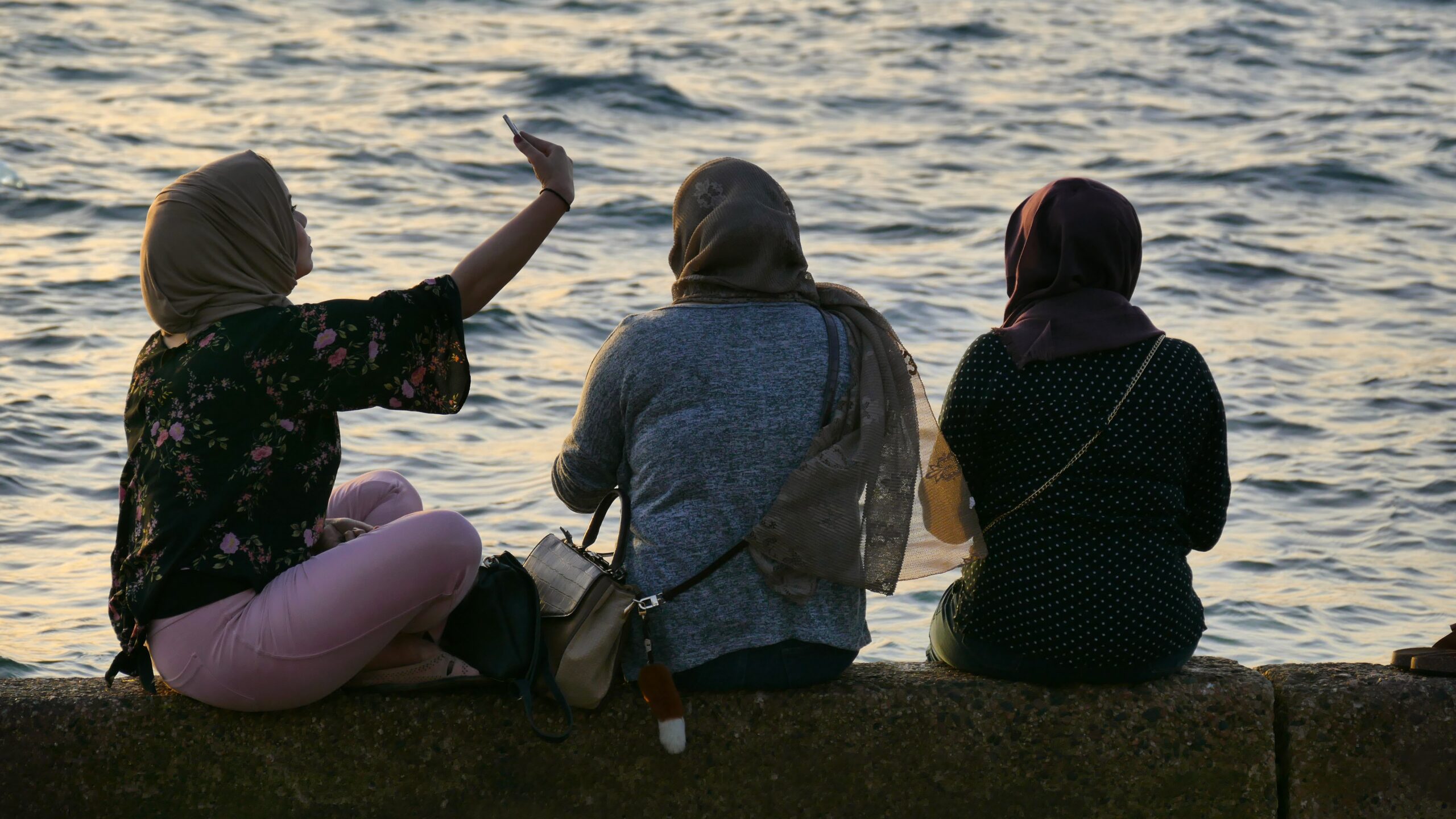 Muslim women by the water taking selfie