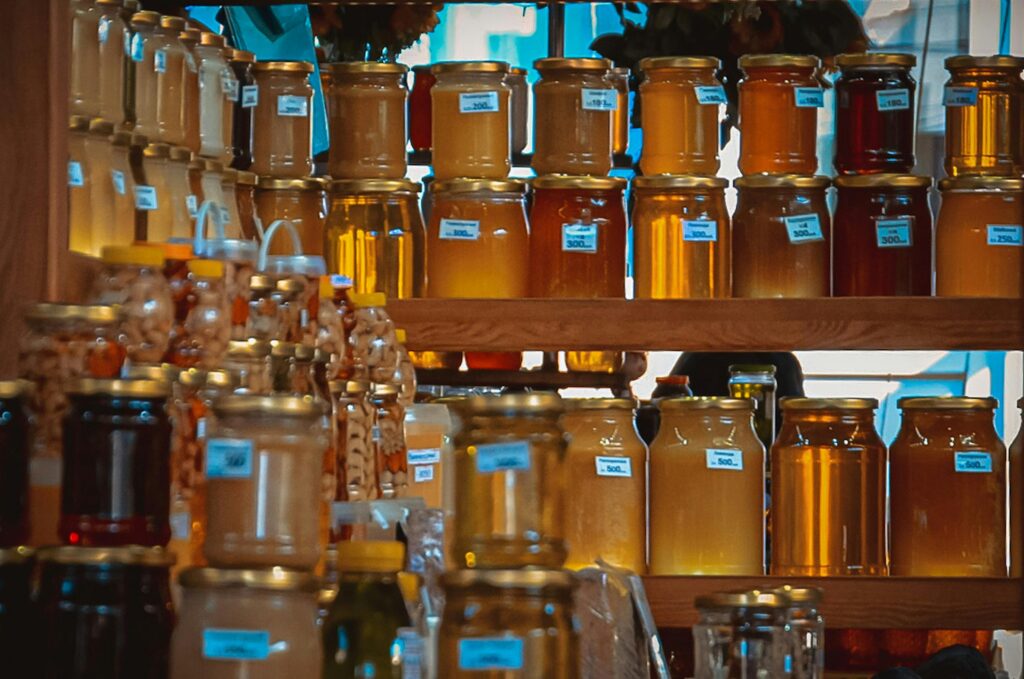 Jars of different colour honey stacked on shelf